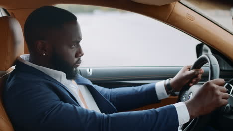 side view of afro man driving alone at car. african man riding at modern vehicle