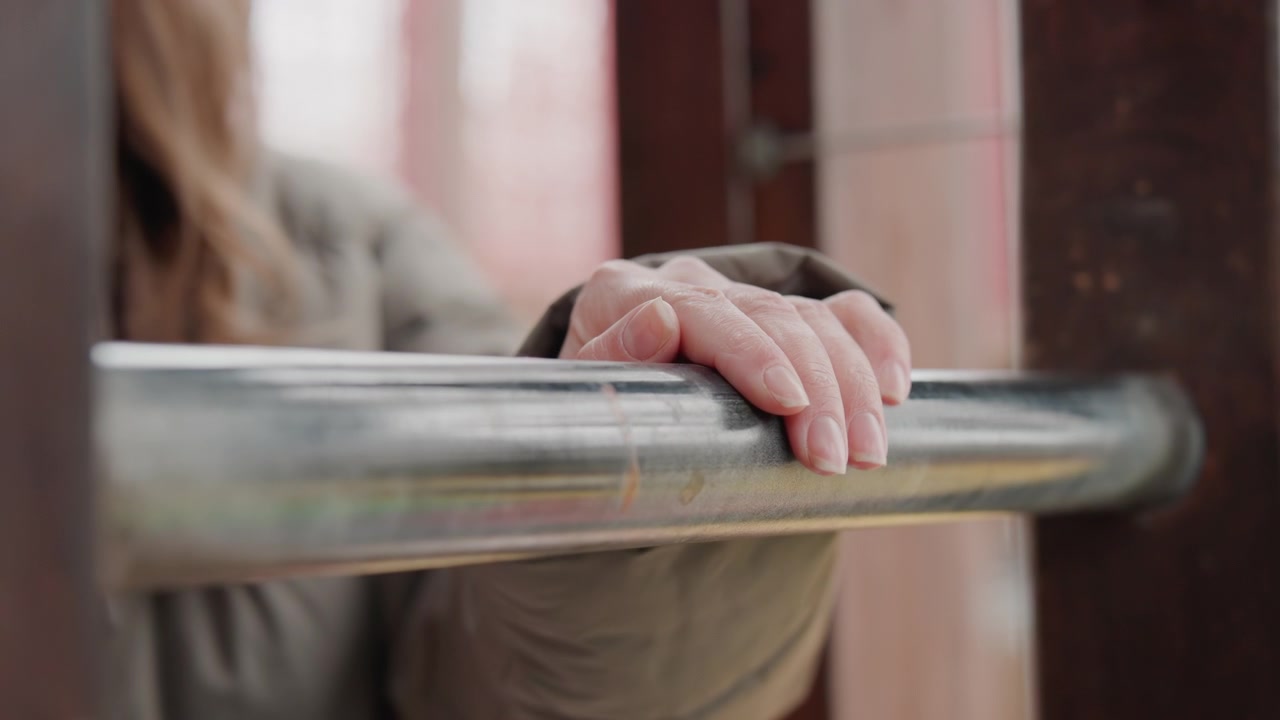Consistent grip during commute. Focused movement on urban transit route. Steady grasp stabilizes rider on busy public transport. Gentle touch and slow motion capture routine city travel scene