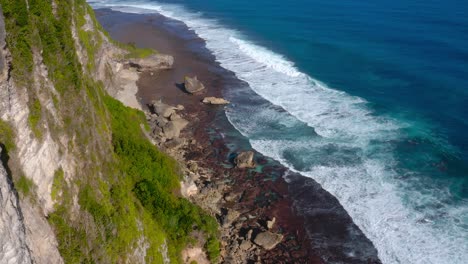 High-forward-aerial-of-ocean-waves-by-Karang-Boma-cliff,-Indonesia