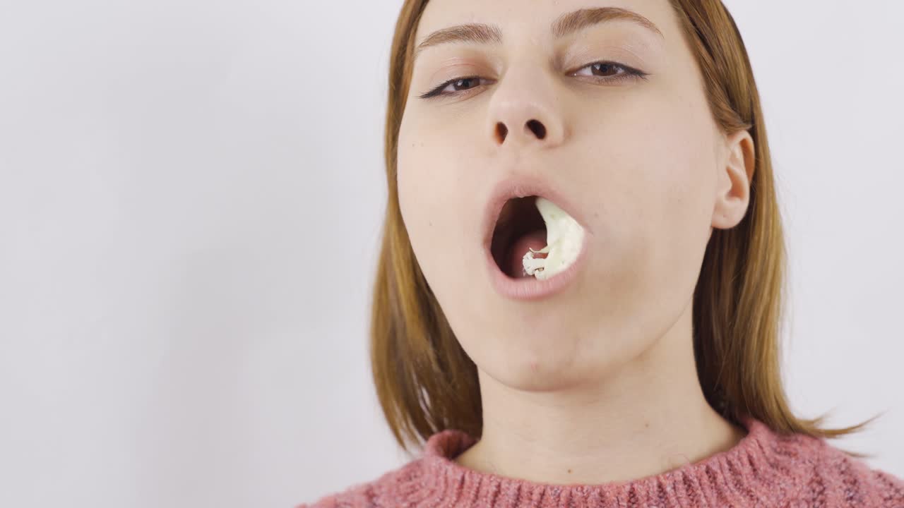 retrato en primer plano de una mujer comiendo coliflor, comiendo verduras, comiendo sano.