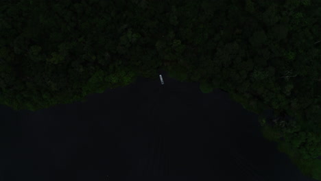 aerial video of a boat sailing towards the forest and entering it