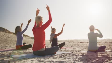 athletic women performing yoga in the beach