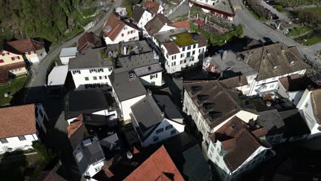 Drone-clip-panning-down-showing-tiled-roofs-of-traditional-white-buildings-in-village,-with-narrow-streets-between-houses