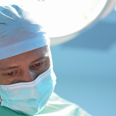 portrait of plastic surgeon in medical mask. doctor's face during operation of liposuction against medical lamp backdrop