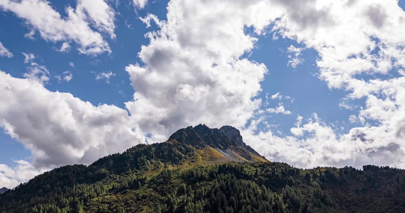 Hyperlapse di nuvole che turbinano attorno a una vetta verde in una giornata di sole nel Passo del Maloja, Alpi Svizzere