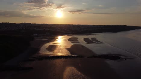 Golden-heavenly-sunset-rays-aerial-view-reflected-over-romantic-illuminated-beach-coastline