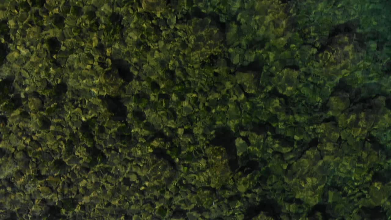 textura de agua abstracta con fondo colorido de guijarros de lago que reflejan los rayos solares