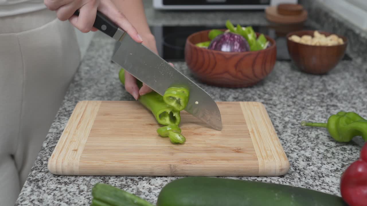 Woman chopping green pepper in kitchen