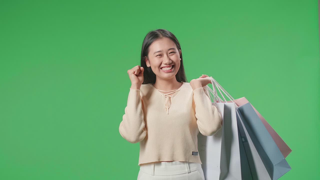An Asian Shopping Woman Holding Shopping Bags Up Being Happy And Smiling To Camera While Standing In Front Of Green Screen