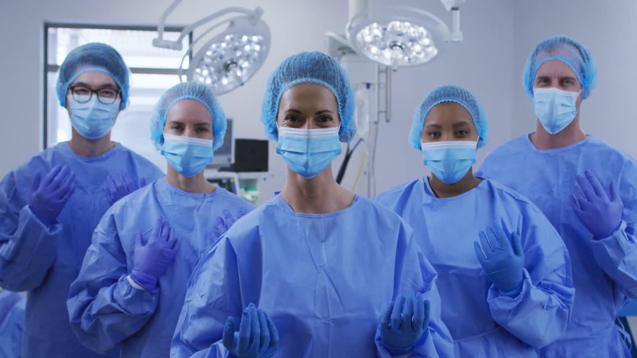 diversos cirujanos que usan máscaras faciales, gorras quirúrgicas y ropa protectora en el quirófano