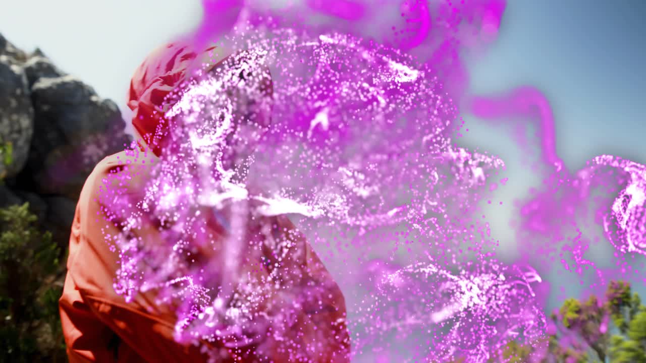 Demo tecnologica che mostra un escursionista con giacca rossa che alza il polso attivando un vortice di energia viola-rosa su una cengia.