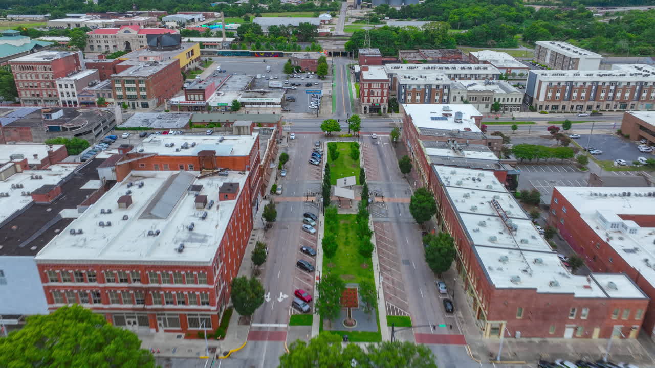 Hyperlapse aereo catturato a giugno 2022 sopra il traffico urbano su Poplar Street, circondata da edifici storici a Macon, GA, verso il ponte ferroviario alla fine del video.