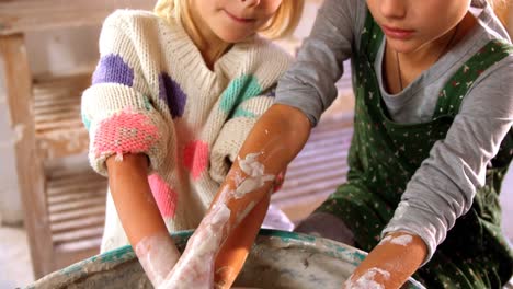 girl assisting her sister while making a pot