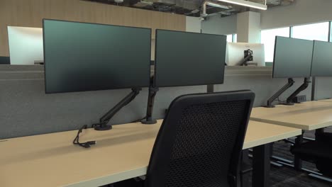 room with workstations equipped with modern technological equipment installed on long wooden desks