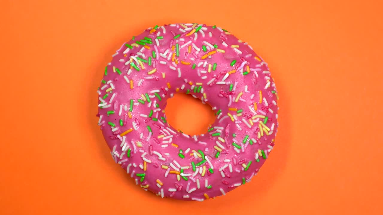 saboroso y fresco rosquilla rosquilla macro disparo de primer plano girando en un fondo naranja.