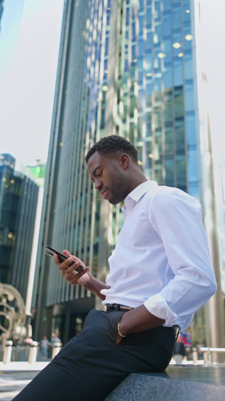 Vertical Video Of Young Businessman In Shirt Sleeves Using Mobile Phone Standing Outside Offices In The Financial District Of The City Of London UK Shot In Real Time