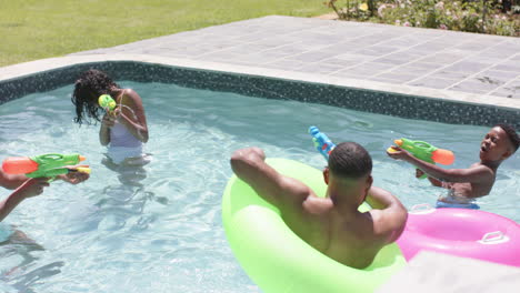 Felices-Padres-Afroamericanos,-Hijo-E-Hija-Jugando-Con-Pistolas-De-Agua-En-La-Piscina,-Cámara-Lenta