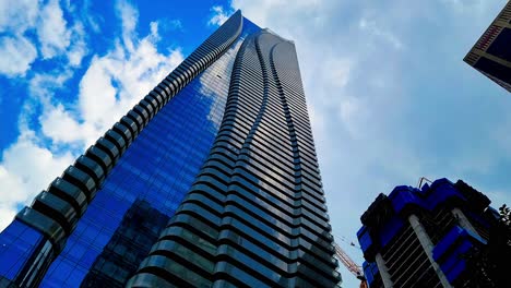 Yonge-and-Bloor-looking-up-mirrored-clouds-on-modern-buildings-sunny-day-while-new-skyscrapers-are-being-built-and-birds-are-flying-over-and-the-weather-is-changing