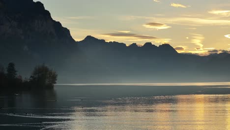 sunset over a calm lake with mountains in the background