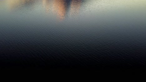 Mount-Fuji-silhouette-at-dusk,-reflecting-on-calm-lake-waters-with-clouds