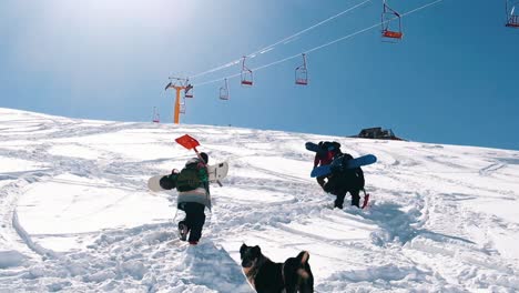 slow motion: snow boarders walking up the mountain. camera moving slowly behind group of snowboarder walking up the mountain