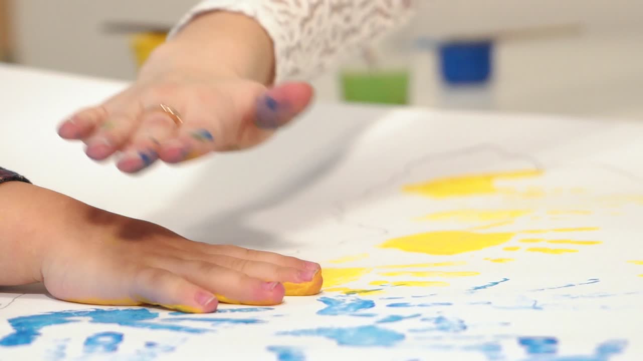 Child making hand prints on paper. Early childhood education. Little painter.