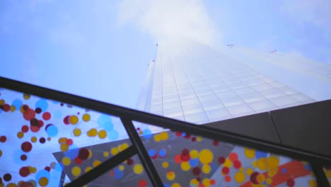 looking up at london colourful skyscrapers downtown, blue sky with light clouds with reflections on the buildings