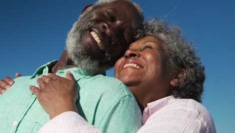 una pareja de mayores enamorados sonriendo en la playa.