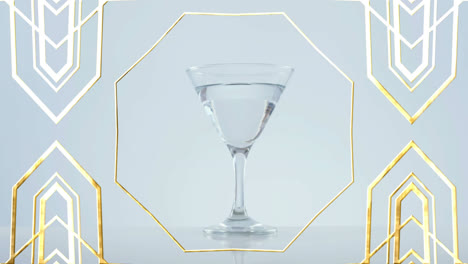 golden frame design pattern over olives falling into cocktail glass against grey background