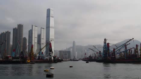 a boat crosses the frame as in the background shows the financial district of hong kong.