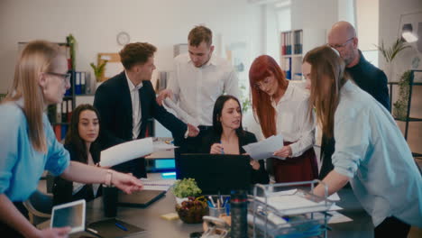 Confident-businesswoman-explaining-employees-over-laptop-in-office.