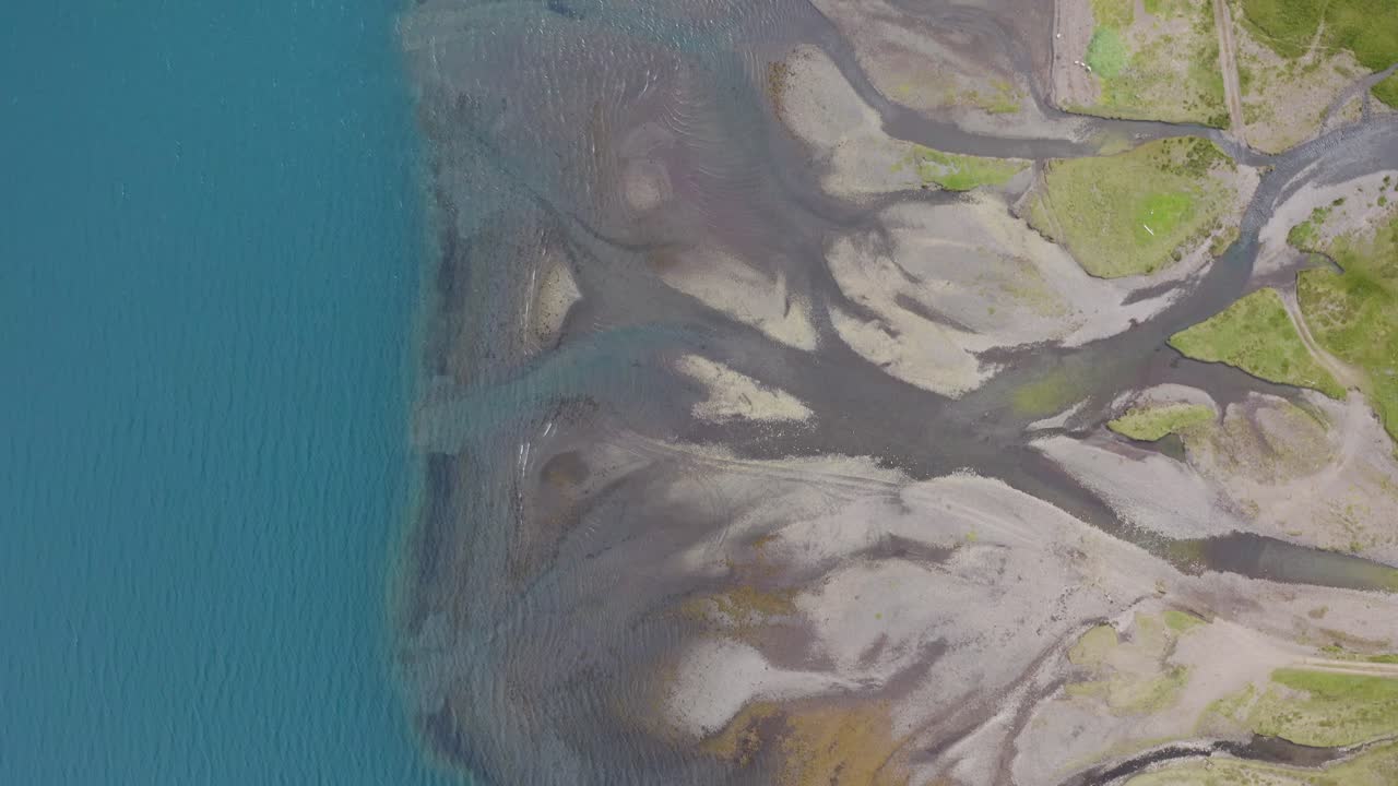 tomada aérea de arriba hacia abajo que muestra el delta del río en la isla de islandia que desemboca en el océano azul - patrón de paisaje desde arriba