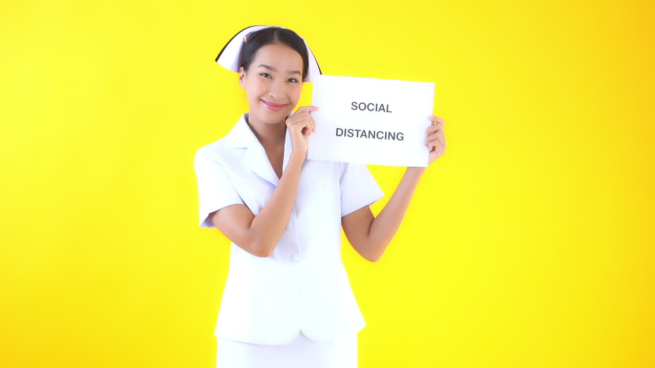 Asian woman nurse or doctor shows the writing print on paper message social distancing