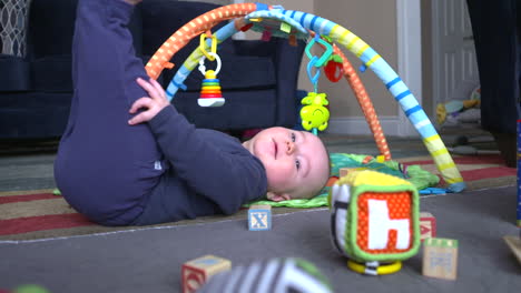 a cute baby boy rolling around and playing with toys