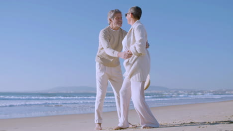 feliz pareja caucásica senior bailando en la playa en un día soleado