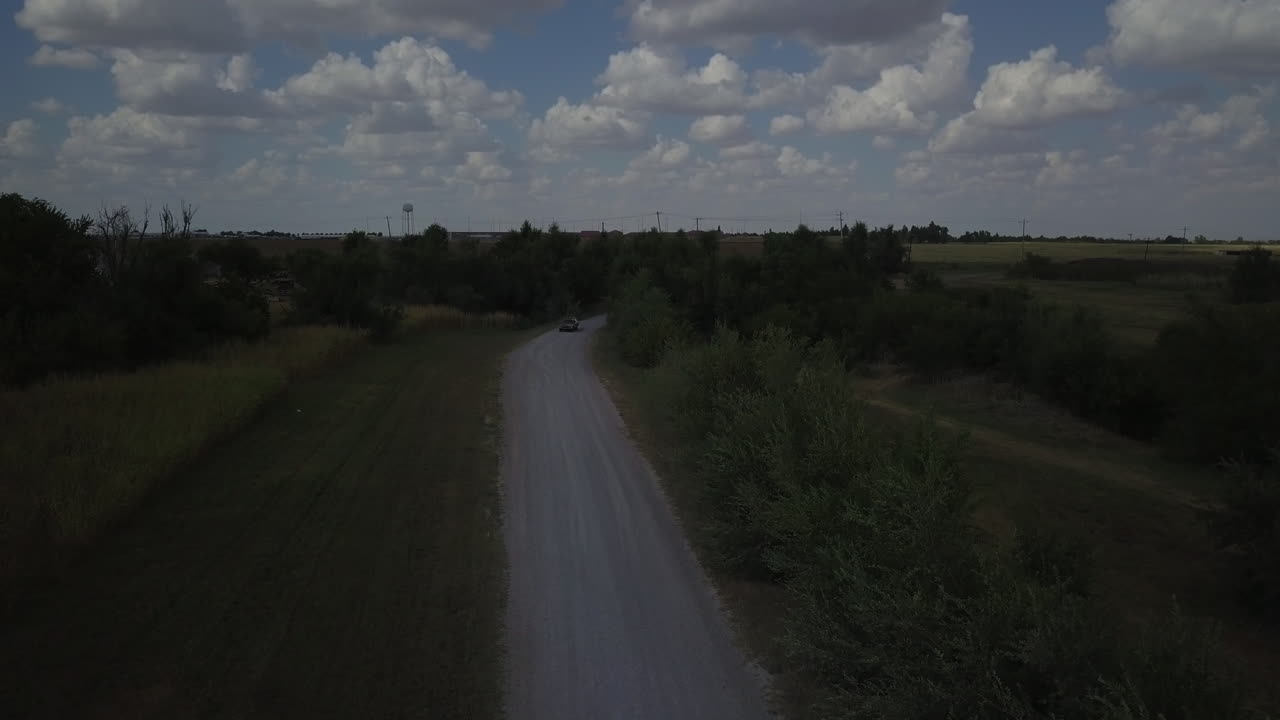 Ripresa aerea in tracking di un'auto rossa che percorre una strada tranquilla.
