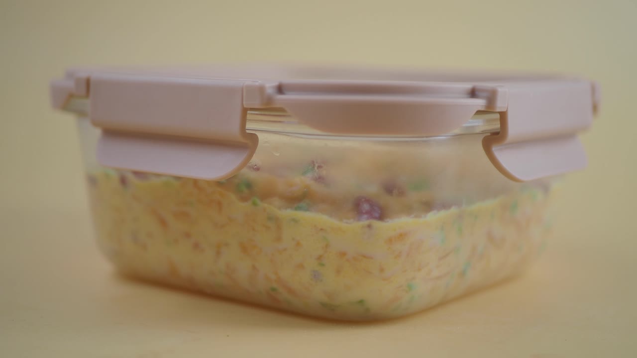 Cibo in un contenitore rettangolare trasparente con coperchio rosa