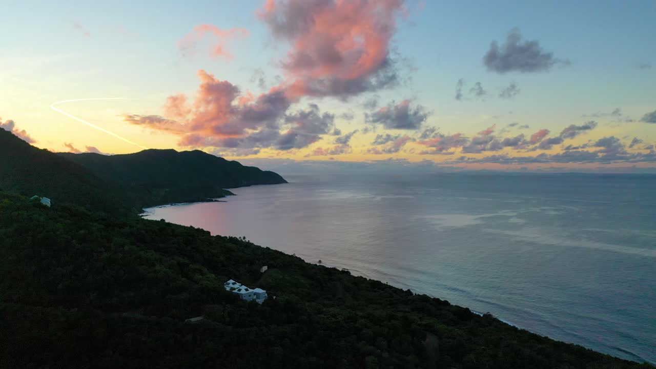Vibrant pink and blue skies glow over St. Croix’s coastline as a lush peninsula stretches into calm ocean waters, creating a peaceful tropical vista seen from above