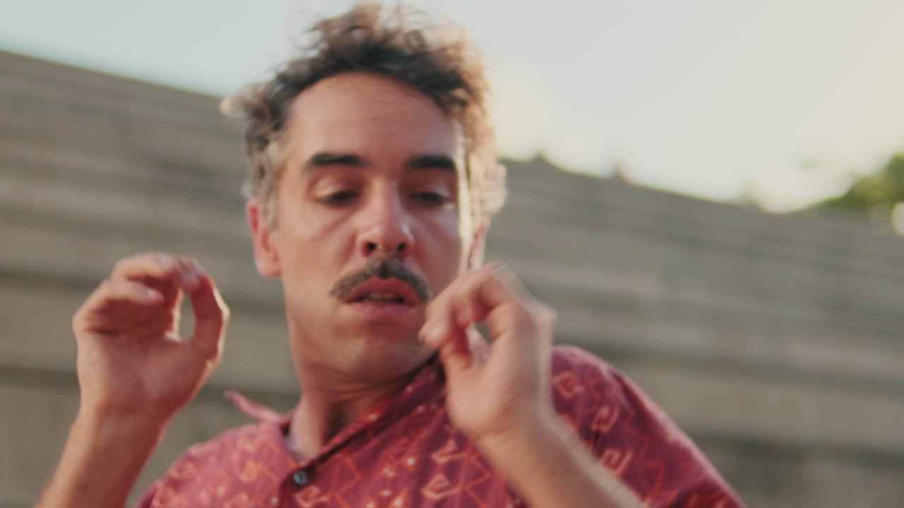 Uomo con i baffi che si sistema la camicia e i capelli in una giornata calda
