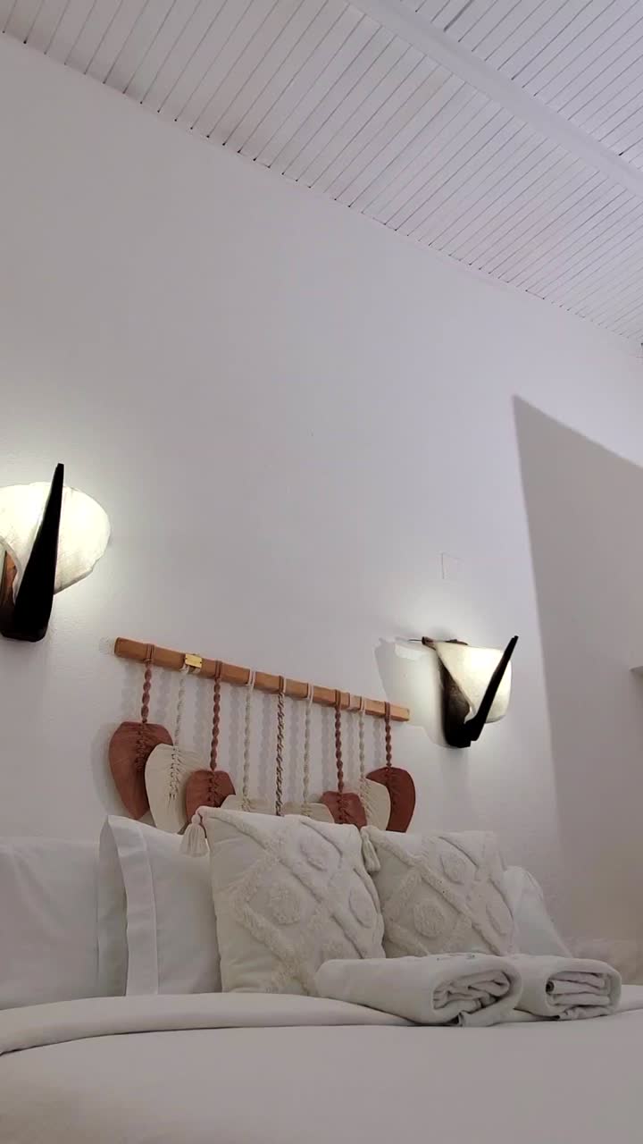 Tranquil, slow-motion view of cozy, white bedroom with warm lighting