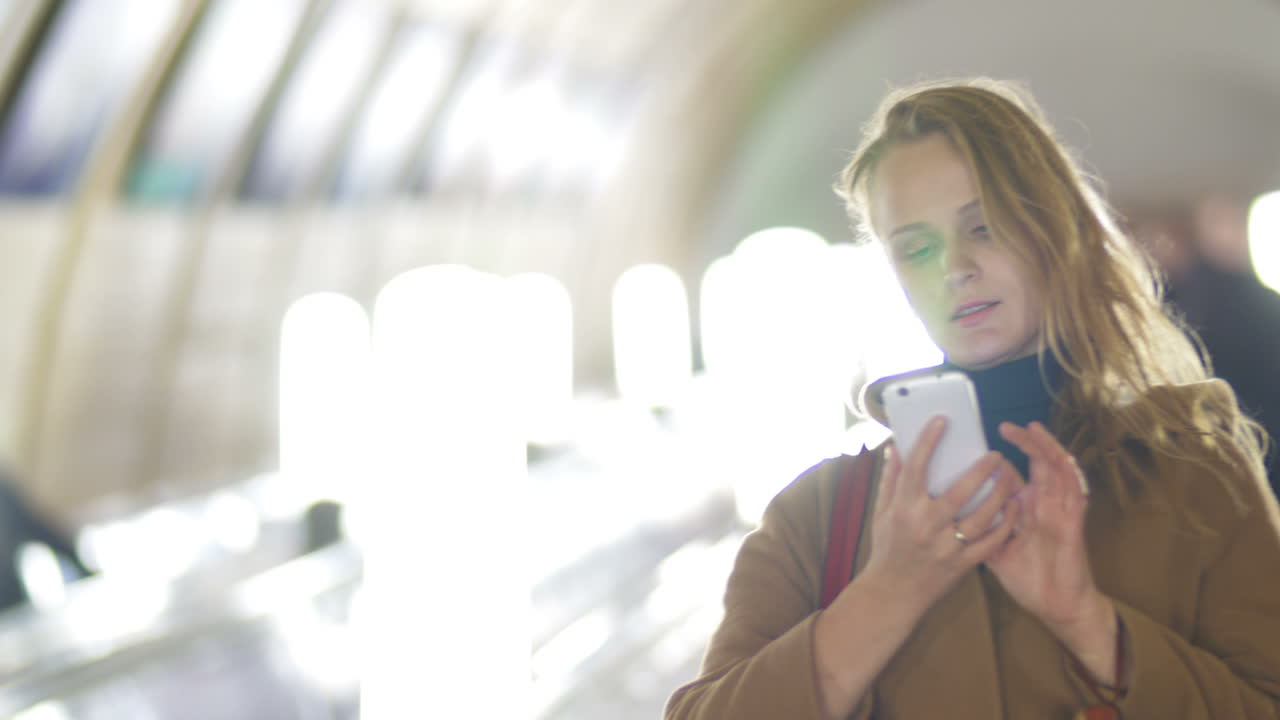 mujer con teléfono inteligente en la escalera mecánica del metro