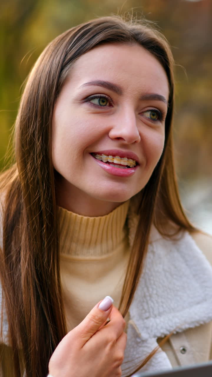 Young charming lady working with laptop. Beautiful lady online studying outdoor in park. Vertical video