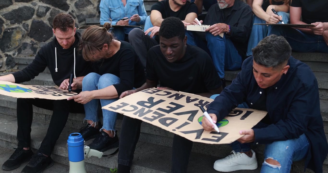 Gruppo eterogeneo di attivisti che preparano cartelli di protesta per una manifestazione sul cambiamento climatico.