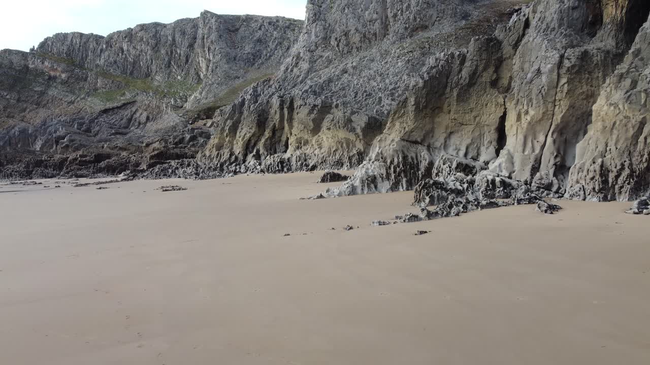 Sandy Beach with Jagged Rocks with Small Sea Caves - Aerial Drone Shot 4K