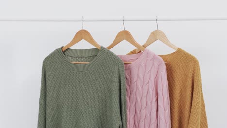 Video-of-three-multi-coloured-sweaters-on-hangers-and-copy-space-on-white-background