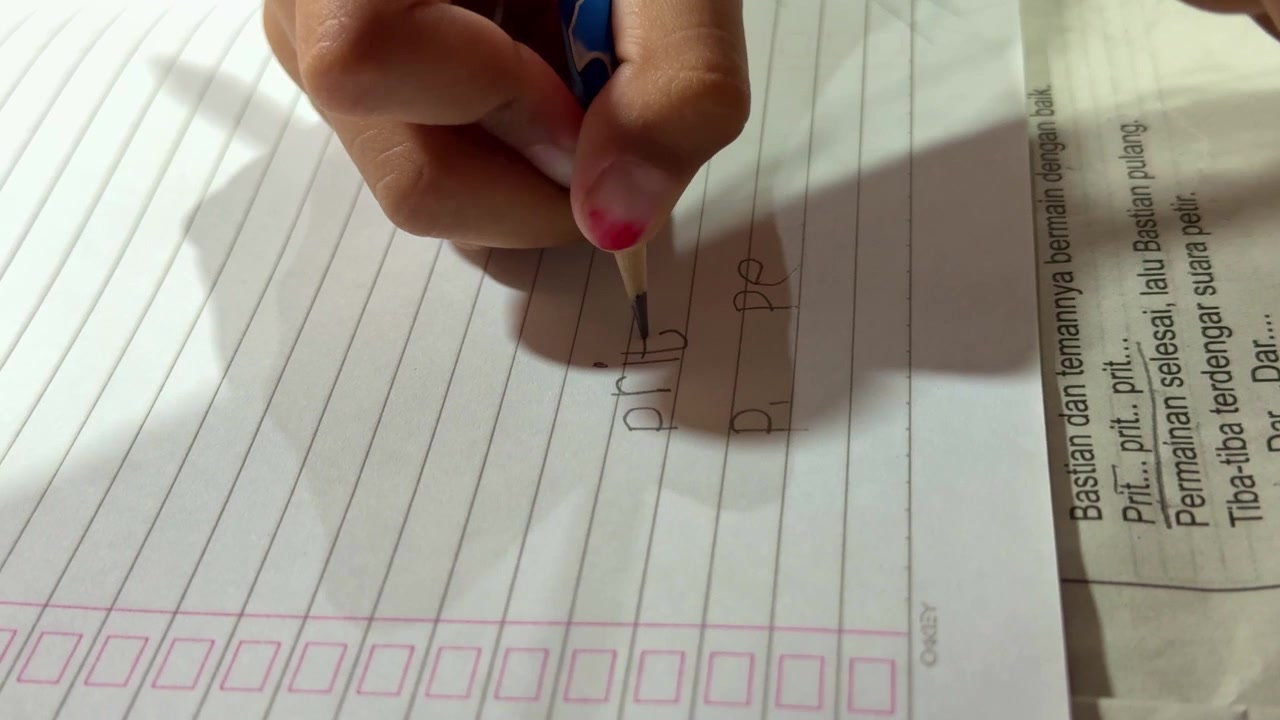 Child writing letters with pencil on notebook close up, learning handwriting, education and school activity concept.