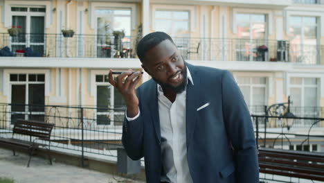 Afro-guy-speaking-on-speakerphone-outside.-Business-man-talking-phone-outdoors