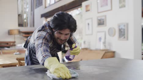 happy caucasian man cleaning worktop in kitchen, copy space, slow motion