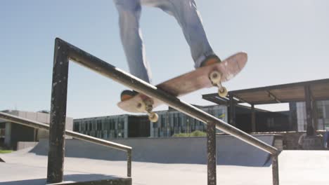 Low-section-of-caucasian-man-riding-and-jumping-on-skateboard-on-sunny-day