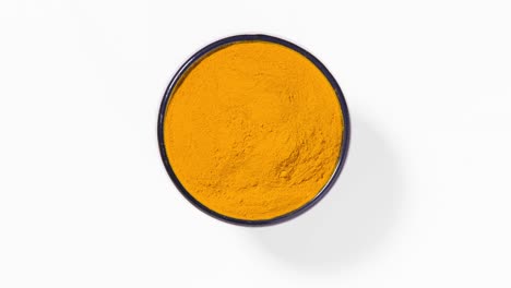 polvo de especias de cúrcuma en un cuenco redondo sobre fondo blanco, bucle sin costuras